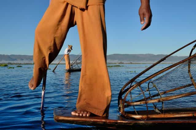 [Cigarette break]. A fisherman on Inle lake (Myanmar) lights a cigarette while his colleague in front poses for tourists. (Photo and caption by Luka Esenko/National Geographic Traveler Photo Contest)