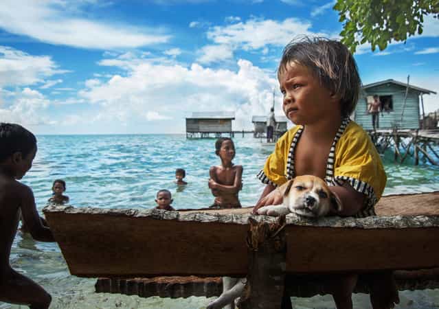 [The beach alone children]. No nationality of Malaysia [Bawo – Rotter] children, with sadness alone on the beach, watching the kids in the game. Location: Malaysia, Semporna. (Photo and caption by He Yuanquan/National Geographic Traveler Photo Contest)
