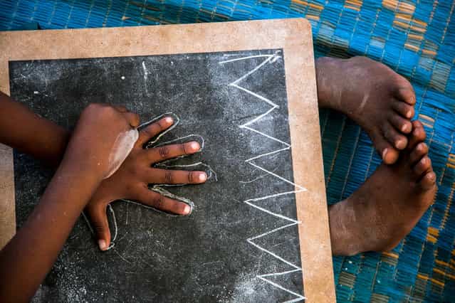 [First drawing]. A child in a nursery Zanzibar draws his hand on a blackboard. Location: Tanzania. (Photo and caption by Beniamino Pisati/National Geographic Traveler Photo Contest)