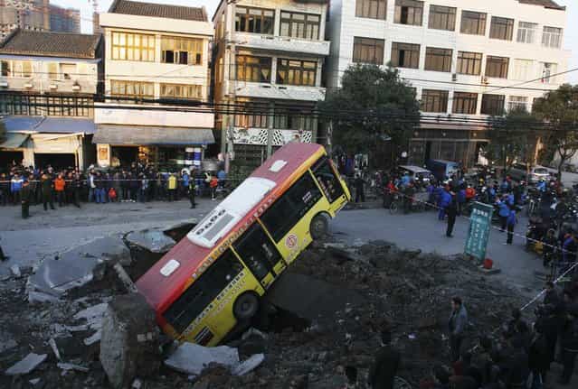 A bus, after falling into a pit created by an underground explosion in Rui'an, Zhejiang province, on January 16, 2011. An explosion on a road in east China's Zhejiang Province tossed a bus without passengers four meters into the air, injuring the driver and a 6-year-old boy on the roadside, local fire fighters said on Sunday. The cause of the explosion was under investigation, Xinhua News Agency reported. (Photo by Reuters/China Daily via The Atlantic)