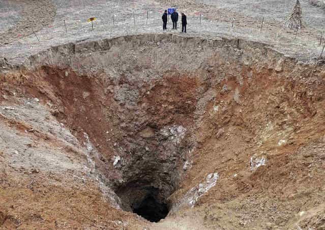 People stand next to a 24.9 metre (82 feet) diametre pit at a village in Guangyuan, Sichuan province, February 28, 2013. According to local media the pit formed on a karst landform last year after the ground surface kept sinking for six days in September. The investigators said the pit may face further sinking after rains due to its geological conditions. (Photo by Reuters/Stringer via The Atlantic)