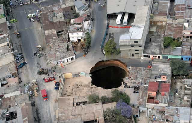 Aerial view of a huge hole caused after a collapse in the sewage system in the neighborhood of San Antonio, north of Guatemala city, on February 23, 2007. Three people were killed in the collapse, as twelve homes were swallowed up. (Photo by Orlando Sierra/AFP Photo via The Atlantic)