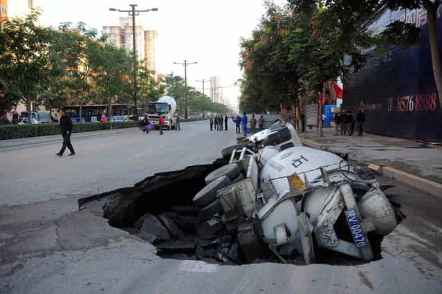 A man walks past a cement truck which fell into a pit after the road caved in, in Xi'an, Shaanxi province September 28, 2012. No casualty was reported, according to local media. (Photo by Reuters/China Daily via The Atlantic)