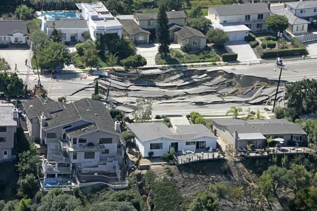 Three homes damaged from a sinkhole sit on the edge of a hill whose lower area collapsed onto other homes in the LaJolla section of San Diego, on October 4, 2007. (Photo by Chris Park/AP Photo via The Atlantic)