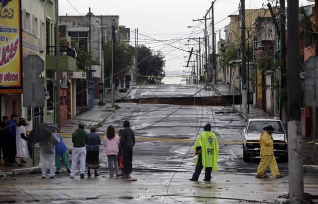 Neighbors gather near the site of a huge sinkhole in Guatemala City, on May 30, 2010. (Photo by Daniel LeClair/Reuters via The Atlantic)
