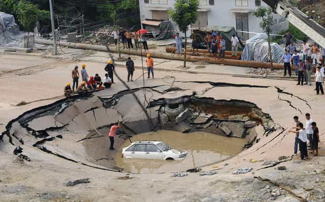 A stranded car is hoisted from a collapsed road surface in Guangzhou, Guangdong province, on September 7, 2008. (Photo by Reuters/China Daily via The Atlantic)