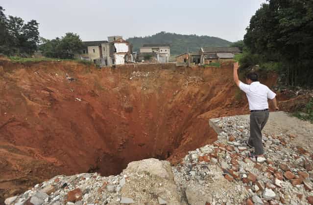 A local resident throws a stone into a sinkhole near Qingquan primary school in Dachegnqiao town, Hunan province, on June 15, 2010. No causalities had been reported and the reason for the appearance of the hole remains unclear. (Photo by Reuters/Stringer via The Atlantic)