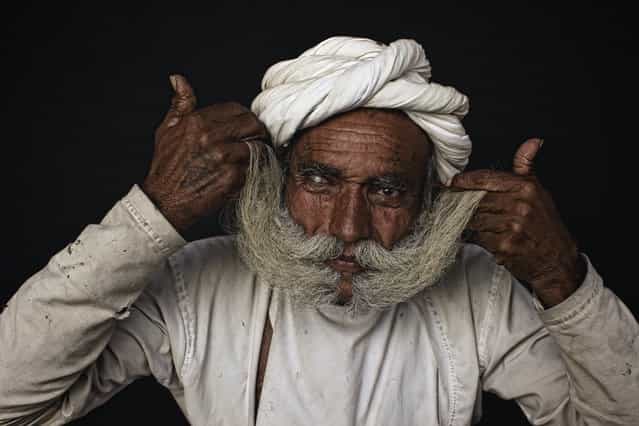 [A big moustache]. Rabari elder showing off his big moustache, the bigger the moustache the more status. Rabari men wear red turbans and white clothes. Sometimes they might use white turbans also. They wear silver bracelets and golden earrings The men like smoking tobacco in Chillums (small Pipe). They also sit together and drink Opium mixed with water, during festivals and ceremonies, after offering it to Gods. Custom is to offer it to each other as well. Location: Image taken close to Mt. Abu, South Rajahstan, India. (Photo and caption by Ingetje Tadros/National Geographic Traveler Photo Contest)