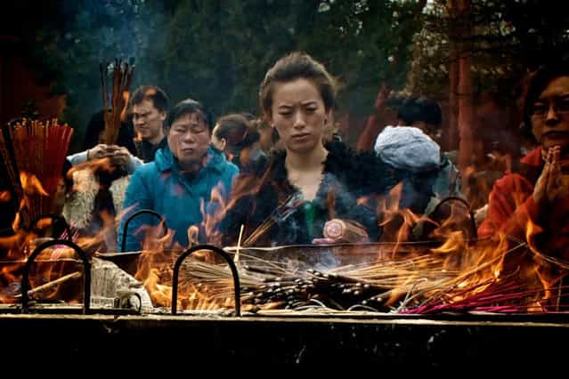 [Young Woman Praying, Lama Temple, Beijing]. At the Lama Buddhist Temple Complex in Beijing, this young woman was lost in thought or prayer, her face slightly distorted by the flames. (Photo and caption by Ben Longland/National Geographic Traveler Photo Contest)