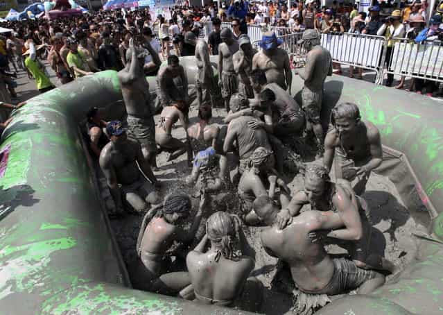 Participants wrestle in a mud pool during the Boryeong Mud Festival at Daecheon Beach in Boryeong, South Korea, Saturday, July 20, 2013. The 16th annual mud festival features mud wrestling and mud sliding. (Photo by Ahn Young-joon/AP Photo)