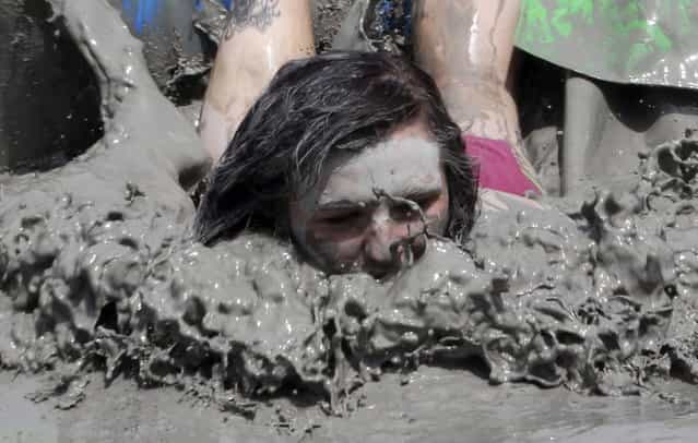 A foreign tourist swims in a mud pool during the Boryeong Mud Festival at Daecheon Beach in Boryeong, South Korea, Saturday, July 20, 2013. The 16th annual mud festival features mud wrestling and mud sliding. (Photo by Ahn Young-joon/AP Photo)