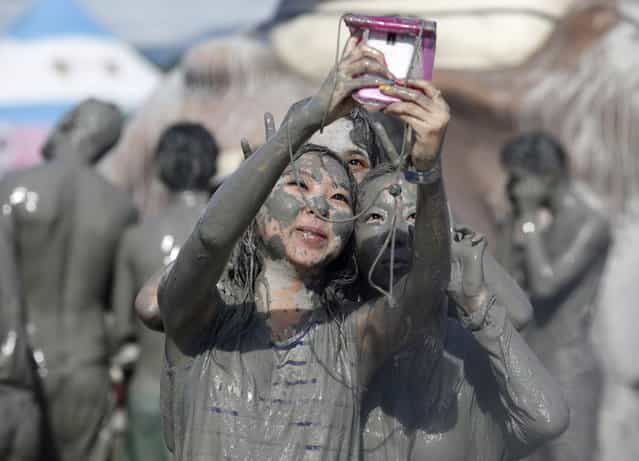 Tourists take pictures with a mobile phone after playing in the mud during the Boryeong Mud Festival at Daecheon beach in Boryeong, about 190 km (118 miles) southwest of Seoul, July 19, 2013. About 2 to 3 million domestic and international tourists visit the beach during the annual mud festival, according to the festival organisers. (Photo by Lee Jae-Won/Reuters)