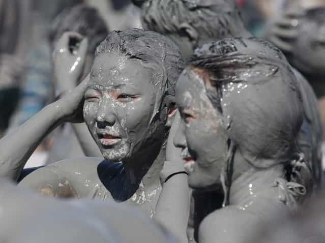 Tourists play in the mud during the Boryeong Mud Festival at Daecheon beach in Boryeong, about 190 km (118 miles) southwest of Seoul, July 19, 2013. About 2 to 3 million domestic and international tourists visit the beach during the annual mud festival, according to the festival organisers. (Photo by Lee Jae-Won/Reuters)
