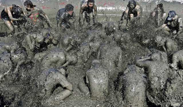 People play in the mud during the Boryeong Mud Festival at Daecheon beach in Boryeong, South Korea, on July 19, 2013. southwest of Seoul. About 2 to 3 million people visit the beach during the annual mud festival. (Photo by Lee Jae-Won/Reuters)