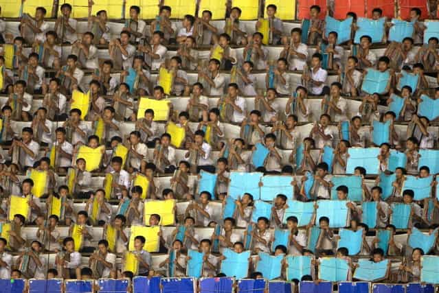 Performers warm up prior to an [Arrirang Festival mass games display] at the 150,000-seat Rungnado May Day Stadiumin Pyongyang on July 26, 2013. Arrirang performances feature some 100,000 participants to create a 'synchronized socialist-realist spectacular in a 90 minute display of gymnastics, dance, acrobatics, and dramatic performance, in a highly politicized package' according to the China-based North Korean travel company Koryo Tours. North Korea is preparing to mark the 60th anniversary of the end of the Korean War which ran from 1950 to 1953, with a series of performances, festivals, and cultural events culminating with a large military parade. (Photo by Ed Jones/AFP Photo)