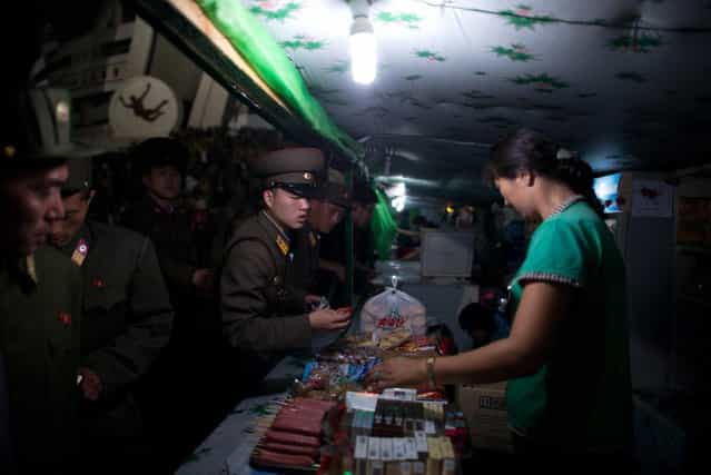 Noth Korean soldiers buy snacks as they leave an [Arrirang Festival mass games display] at the 150,000-seat Rungnado May Day Stadiumin Pyongyang on July 26, 2013. Arrirang performances feature some 100,000 participants to create a 'synchronized socialist-realist spectacular in a 90 minute display of gymnastics, dance, acrobatics, and dramatic performance, in a highly politicized package' according to the China-based North Korean travel company Koryo Tours. North Korea is preparing to mark the 60th anniversary of the end of the Korean War which ran from 1950 to 1953, with a series of performances, festivals, and cultural events culminating with a large military parade. (Photo by Ed Jones/AFP Photo)