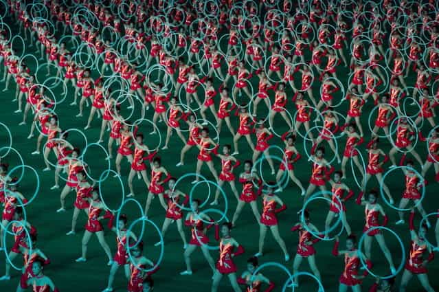 Dancers use hoops during an [Arrirang] performance at the 150,000-seat Rungnado May Day Stadium in Pyongyang on July 26, 2013. Arrirang performances feature some 100,000 participants to create a [synchronized socialist-realist spectacular in a 90 minute display of gymnastics, dance, acrobatics, and dramatic performance, in a highly politicized package] according to the China-based North Korean travel company Koryo Tours. North Korea is preparing to mark the 60th anniversary of the end of the Korean War which ran from 1950 to 1953, with a series of performances, festivals, and cultural events culminating with a large military parade. (Photo by Ed Jones/AFP Photo)