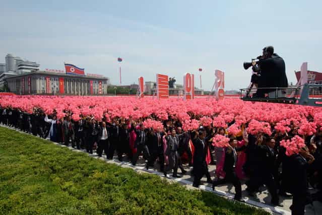 North Koreans wave flowers as they take part in a military parade past Kim Il-Sung square marking the 60th anniversary of the Korean war armistice in Pyongyang on July 27, 2013. North Korea mounted its largest ever military parade on July 27 to mark the 60th anniversary of the armistice that ended fighting in the Korean War, displaying its long-range missiles at a ceremony presided over by leader Kim Jong-Un. (Photo by Ed Jones/AFP Photo)