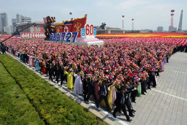 North Koreans wave flowers as they take part in a military parade past Kim Il-Sung square marking the 60th anniversary of the Korean war armistice in Pyongyang on July 27, 2013. (Photo by Ed Jones/AFP Photo)