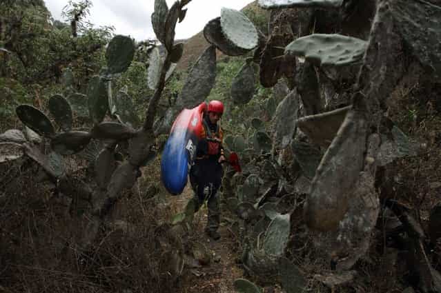 August 25, 2012 – Rio Mantaro, Peru – Amazon Express white water team member Simon Yerov, of Chile, carries his kayak through a cactus field up from the Rio Mantaro. Yerovi was feeling very ill from the contaminated river water. Two other white water members also became ill that night. (Photo by Erich Schlegel/zReportage via ZUMA Press)