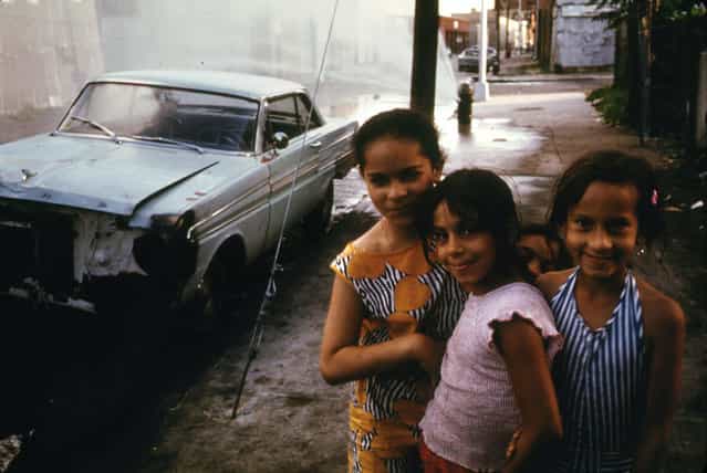 A fire hydrant sprays water behind three young girls on Bond Street in Brooklyn, July 1974. (Photo by Danny Lyon/NARA via The Atlantic)
