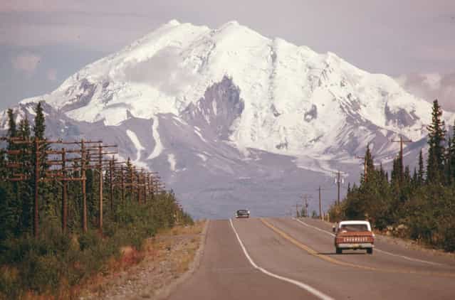 Looking east along Alaska's Glen Highway, toward Mount Drum (Elevation 12,002 Feet) at the intersection of the highway and the under-construction Trans-Alaska Pipeline in August 1974. The 48-inch diameter pipeline will cross the roadway between the two vehicles. The exact point is marked by a pair of wooden stakes along the right shoulder at Mile 673. (Photo by Dennis Cowals/National Archives and Records Administration via The Atlantic)