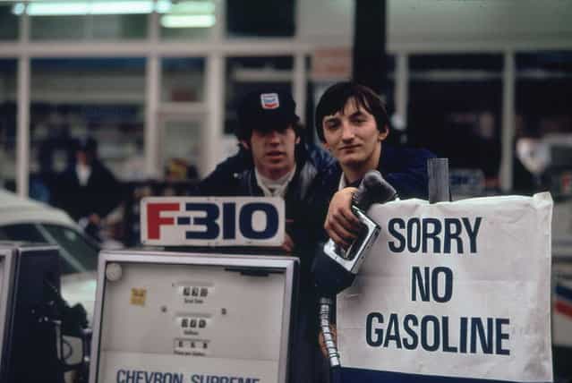Gas station attendants peer over their "Out of Gas" sign in Portland, one day before the state's requested Saturday closure of gasoline stations, November 1973. (Photo by David Falconer/NARA via The Atlantic)