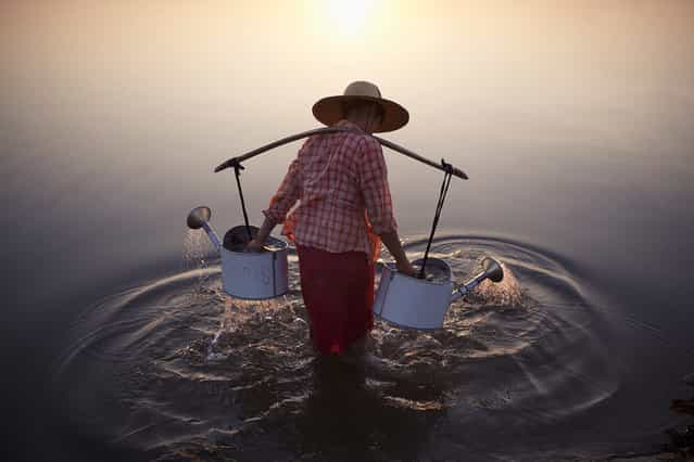 Merit Winner: [Lady in Water]. A lady collects water in the river by a village in Bagan, Myanmar, 2013. Location: Bagan, Myanmar. (Photo and caption by Marcelo Salvador/National Geographic Traveler Photo Contest)