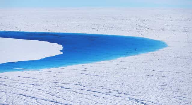 Water stands on part of the glacial ice sheet that covers about 80 percent of Greenland, on July 17, 2013. (Photo by Joe Raedle/Getty Images via The Atlantic)