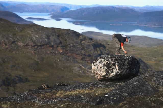 Jason Briner, with the University of Buffalo Department of Geology, looks for the right spot to gather samples of granite to research the age of the local glacial retreat, on July 24, 2013 near Ilulissat. (Photo by Joe Raedle/Getty Images via The Atlantic)