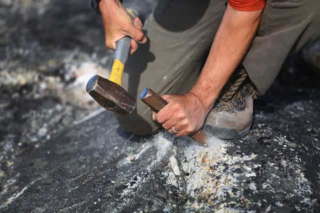 Jason Briner, with the University of Buffalo, uses a hammer and chisel to gather samples of granite to research the age of the local glacial retreat, on July 24, 2013 near Ilulissat. (Photo by Joe Raedle/Getty Images via The Atlantic)
