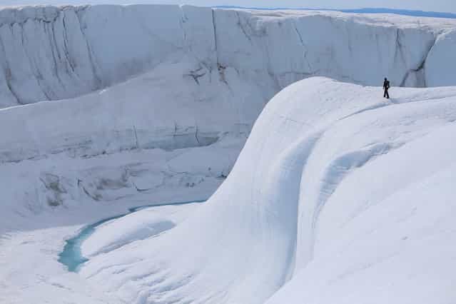 Sarah Das from the Woods Hole Oceanographic Institution looks at a canyon created by a meltwater stream on July 16, 2013 on the glacial ice sheet. (Photo by Joe Raedle/Getty Images via The Atlantic)