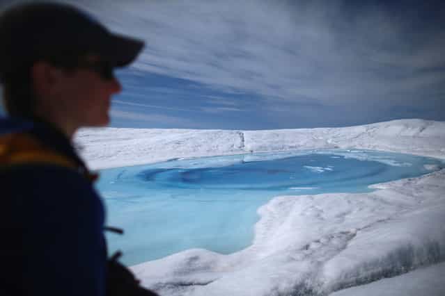 Laura Stevens, graduate student from the Massachusetts Institute of Technology and Woods Hole Oceanographic Institution, walks past a meltwater lake on July 16, 2013. She along with a group of scientists closely monitor the evolution of the surface lakes and the motion of the surrounding ice sheet. (Photo by Joe Raedle/Getty Images via The Atlantic)