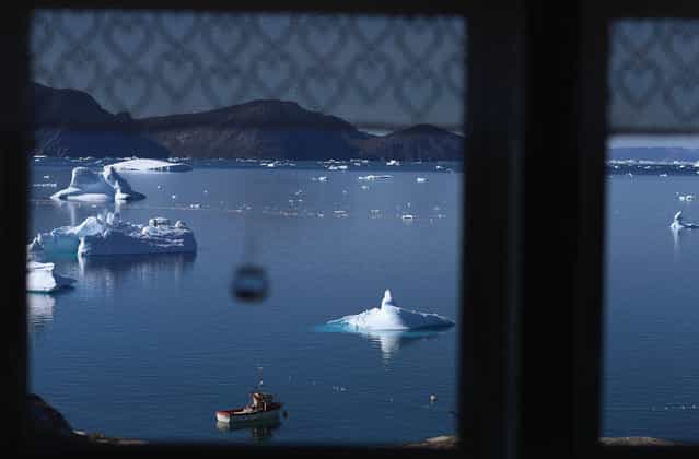 Icebergs, viewed through a kitchen window in Qeqertaq, Greenland, on July 20, 2013. (Photo by Joe Raedle/Getty Images via The Atlantic)