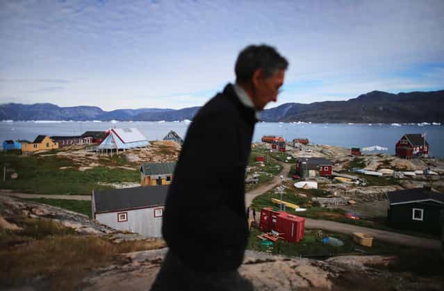A person walks through the village of Qeqertaq, Greenland, on July 20, 2013. As Greenlanders adapt to the changing climate and go on with their lives, researchers from the National Science Foundation and other organizations are studying the phenomena of the melting glaciers and its long-term ramifications for the rest of the world. (Photo by Joe Raedle/Getty Images via The Atlantic)