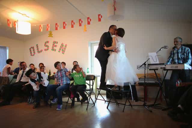 Newlyweds, Adam Olsen and Ottilie Olsen kiss as they stand on chairs in a hall in Qeqertaq, on July 20, 2013. (Photo by Joe Raedle/Getty Images via The Atlantic)