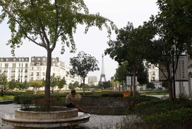 A man sits under a tree at the Tianducheng development in Hangzhou, Zhejiang Province August 1, 2013. Tianducheng, developed by Zhejiang Guangsha Co. Ltd., started construction in 2007 and was known as a knockoff of Paris with a scaled replica of the Eiffel Tower standing at 108 metres (354 ft) and Parisian houses. Although designed to accommodate at least 10 thousand people, Tianducheng remains sparsely populated and is now considered as a [ghost town], according to local media. (Photo by Aly Song/Reuters)