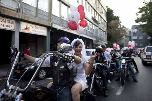Bride Yulia Tagil sits on the backseat of a bike as she arrives for her alternative wedding ceremony on a square in Tel Aviv July 25, 2010. The alternative wedding ceremony was intended to demonstrate against the current situation in Israel, where the only way for Jews to get married by law is through the Chief Rabbinate. (Photo by Nir Elias/Reuters)