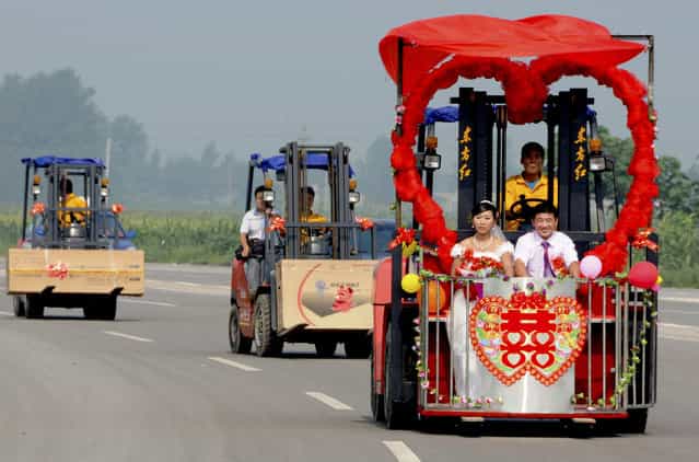 Bridegroom Kong Qingyang and his bride Shen Likun sit on a forklift, which is transformed into a wedding car, during their wedding in Xingtai, Hebei province, August 3, 2011. Kong, a former forklift driver, met his bride Shen, who was a forklift seller, while buying a forklift from her. Picture taken August 3, 2011. (Photo by Reuters/China Daily)