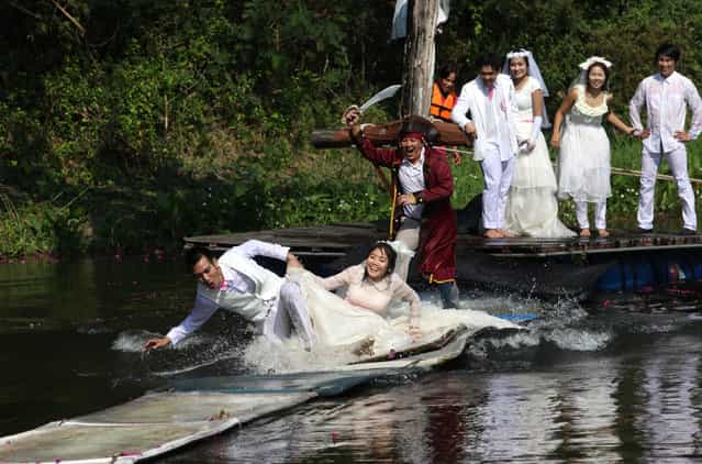 Thai groom and bride, Sorawich Changtor (front L), 28, and Rungnapa Panla (front R), 30, run to escape a man dressed as a pirate as (behind L-R) Prasit Rangsiyawong, 29, Varuttaon Rangsiyawong, 27, Chutima Imsuntear, 37, and Sopon Sapaotong, 41, look on during a wedding ceremony ahead of Valentine's Day in Prachin Buri province, east of Bangkok February 13, 2013. Three Thai couples took part in the wedding ceremony arranged by a Thai resort that aimed to strengthen the relationships of the couples by doing fun activities. (Photo by Kerek Wongsa/Reuters)