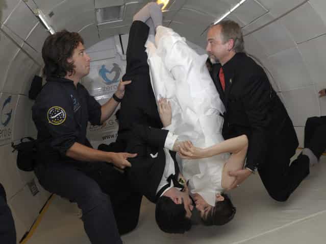 Bride Erin Finnegan and bridegroom Noah Fulmor, both of New York, are helped by Zero Gravity Corporation co-founder Richard Garriott (R), and Bryan Rapoza as they seal their wedding with a kiss, while floating upside down, during the first weightless wedding aboard a specially-equipped Boeing 727, while flying over the Gulf of Mexico after taking off from Titusville, Florida, June 20, 2009. Finnegan and Fulmor floated into matrimony on Saturday thousands of feet (metres) above the Gulf of Mexico in what organizers said was the world's first weightless wedding held in zero gravity conditions. To recreate the weightless experience without going into space, the plane executed parabolic flight maneuvers, climbing sharply and descending several times during the one-hour flight. (Photo by Phelan Ebenhack/Reuters)
