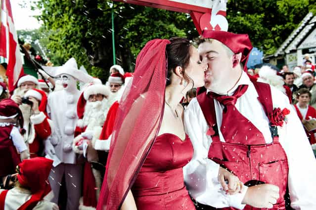 Newlyweds Sine Andersen and Rune Jamrath (R) who is dressed as a pixie, kiss during their wedding at the World Santa Claus Congress 2009, at the amusement park Bakken north of Copenhagen July 20, 2009. More than 150 Santas from all over the world convened for the 52nd congress. The father of the bride (background 2nd L) is the Bakken amusement park Pirrot. (Photo by Casper Christoffersen/Reuters/Scanpix)