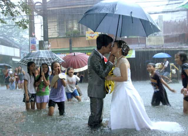 Ramoncito Campo kisses his wife Hernelie Ruazol Campo on a flooded street during a southwest monsoon that battered Manila August 8, 2012. The newly-wed couple pushed through with their scheduled wedding despite severe flooding that inundated wide areas of the capital and nearby nine provinces. (Photo by Reuters/Courtesy of Ramoncito Campo/Handout)