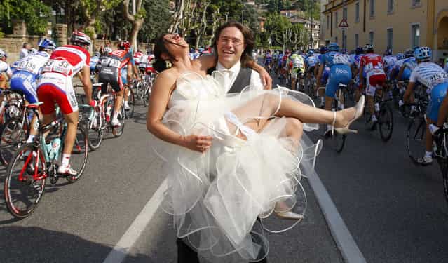 A newly-wed couple pose as cyclists ride past during the second stage from Jesolo to Trieste of the Giro d'Italia, May 10, 2009. Italy's Alessandro Petacchi won the stage while Britain's Mark Cavendish took the leader's pink jersey. (Photo by Stefano Rellandini/Reuters)