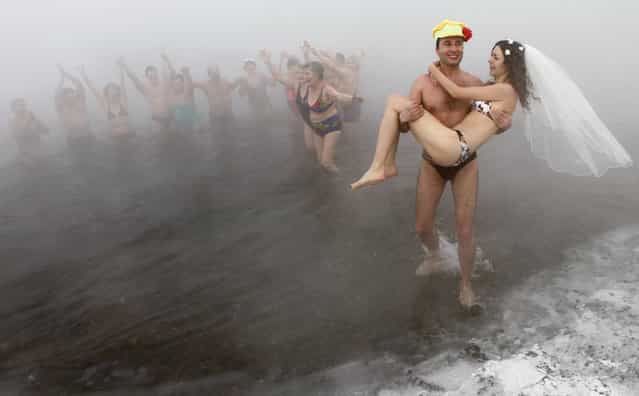 Sergey Kaunov, a member of a local winter swimmers' club, carries his bride Irina Kuzmenko out of water as they celebrate their wedding on the bank of Yenisey River where the air temperature was about -30 degrees Celsius (-22 degree Fahrenheit) in the Russia's Siberian city of Krasnoyarsk, January 22, 2011. Irina does not practice winter bathing, but she did it on the day of their wedding after heating up in a sauna. (Photo by Ilya Naymushin/Reuters)