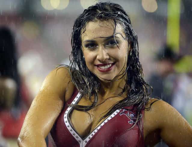 During a rainstorm, a Tampa Bay Buccaneers cheerleader performs during a game against the Baltimore Ravens in Tampa. (Photo by Phelan M. Ebenhack/Associated Press)