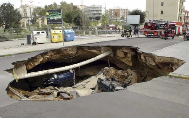 Cars lie in a sinkhole, caused when a road collapsed into an underground cave system, in the southern Italian town of Gallipoli March 30, 2007. There were no injuries in the overnight incident, according to local police. (Photo by Fabio Serino/Reuters)