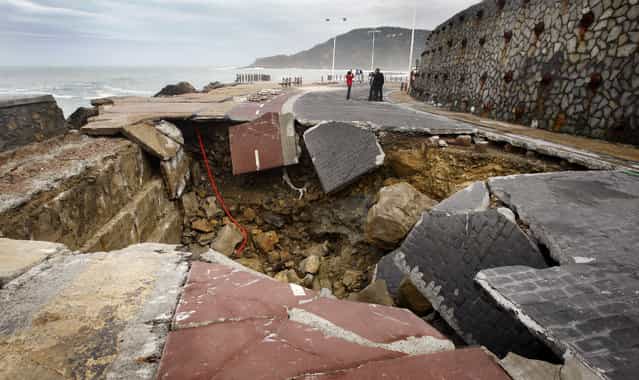 Members of a television crew stand near a hole in the Paseo Nuevo in San Sebastian March 12, 2008. The hole was caused by a storm on Thursday that sunk numerous boats and caused extensive damage in the Biscay area. (Photo by Vincent West/Reuters)