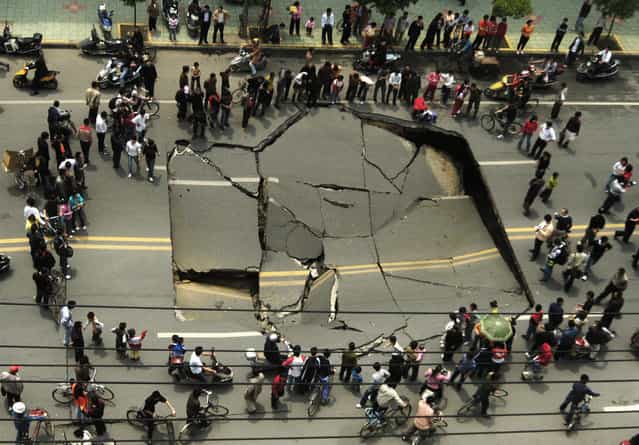 People look at a collapsed section of Shunwai Road in Nanchang, China's Jiangxi province, April 25, 2007. No one was injured in the accident and further investigations are underway, according to local media. Picture taken April 25, 2007. (Photo by Reuters/China Daily)