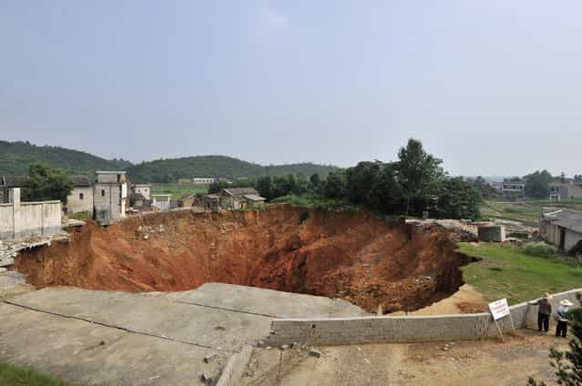 Local residents look at a sinkhole near Qingquan primary school in Dachegnqiao town of Ningxiang, Hunan province June 15, 2010. The hole, 150 meters (492 feet) wide and 50 meters (164 feet) deep, has been growing since it first appeared in January and has destroyed 20 houses so far. No causalities has been reported and the reason for the appearance of the hole remains unclear, local media reported. (Photo by Reuters/Stringer)